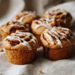 Pumpkin Cinnamon Roll Muffins fresh from the oven with cinnamon swirl and icing drizzle