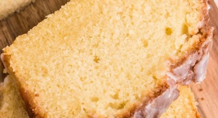 Slice of moist Apple Cider Pound Cake on a plate with autumn leaves