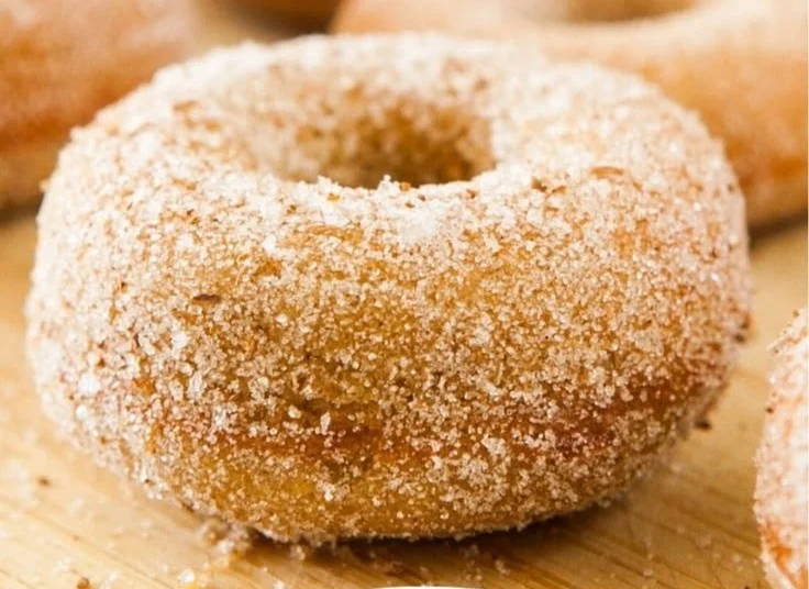 Baked Pumpkin Donuts Recipe 2 Baked pumpkin donuts topped with spices and icing on a wooden table