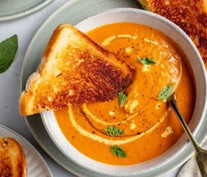 Bowl of comforting roasted tomato soup garnished with fresh basil