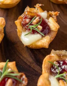 Cranberry Brie Bites: Easy Christmas Party Appetizer 3 Cranberry Brie Bites topped with fresh cranberries and herbs, festive holiday appetizer