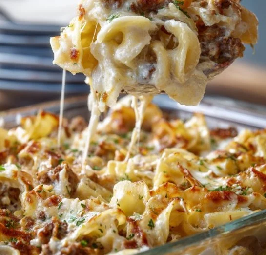 Bowl of easy sour cream beef noodle casserole topped with cheese and herbs