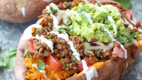 Delicious taco stuffed sweet potatoes topped with cheese and avocado